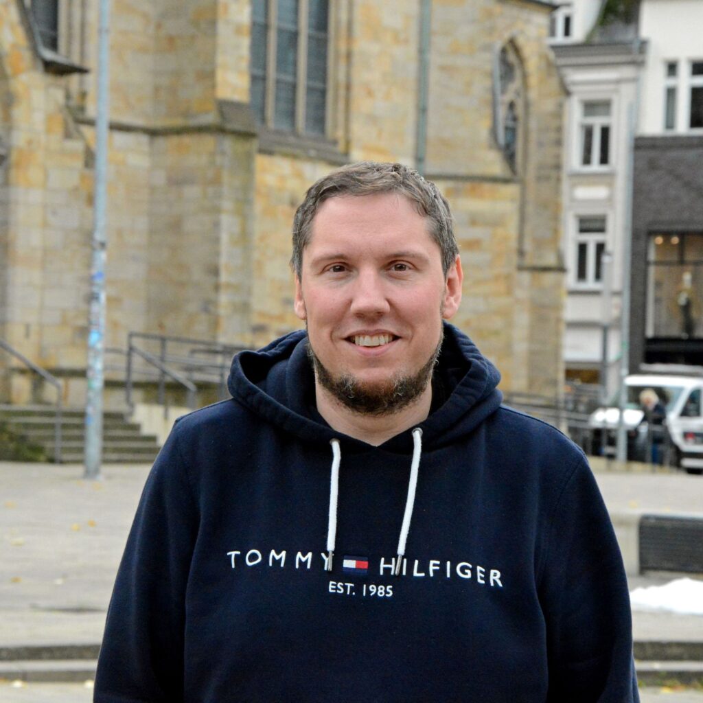Kaplan Markus Nowag steht vor der Sankt-Urbanus-Kirche